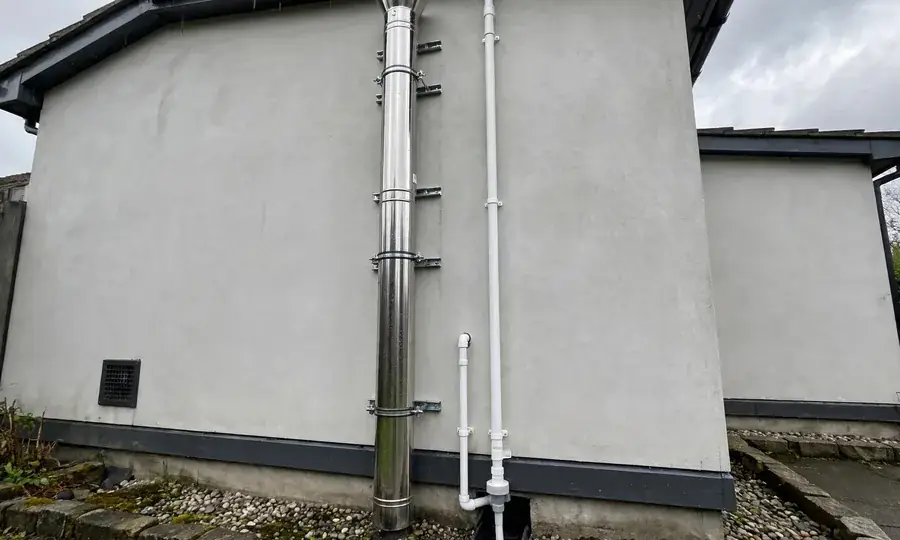Exterior boiler flue and condensate drain pipe on a house wall