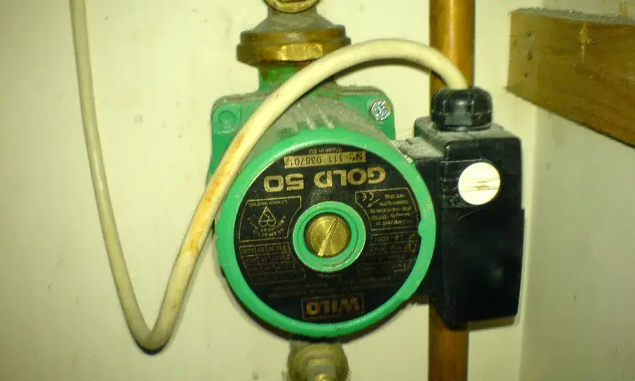 Green circulator pump mounted on heating pipes